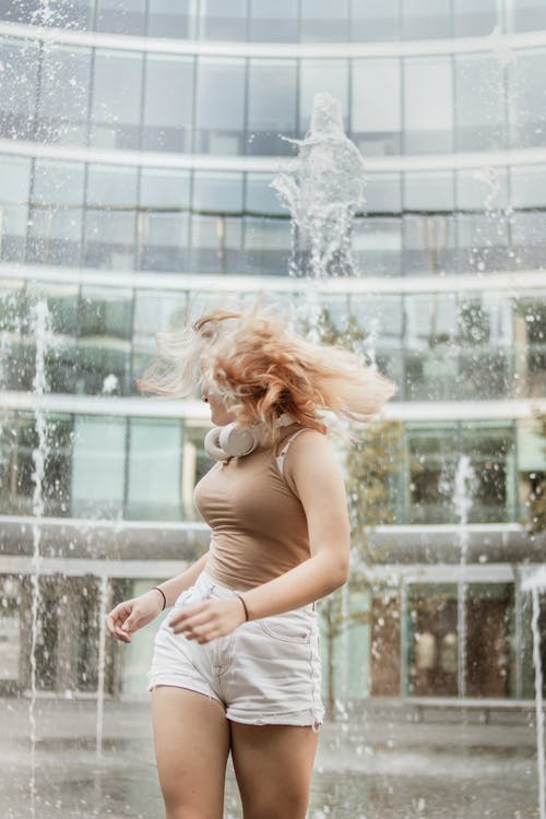 女人站在喷泉旁边的浅焦点照片 · 免费素材图片
