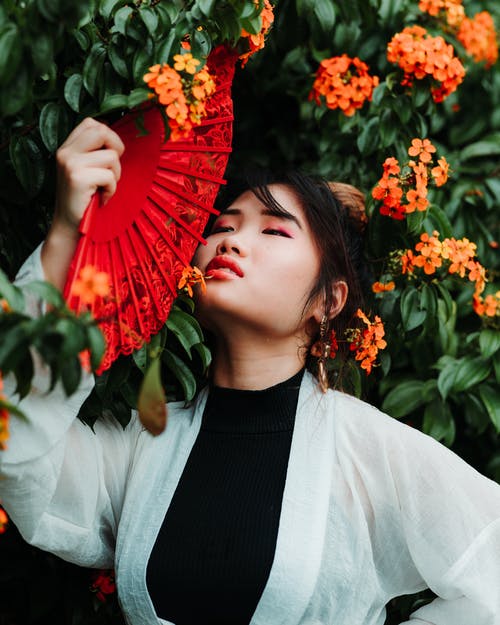 女人抱着手扇的照片 · 免费素材图片