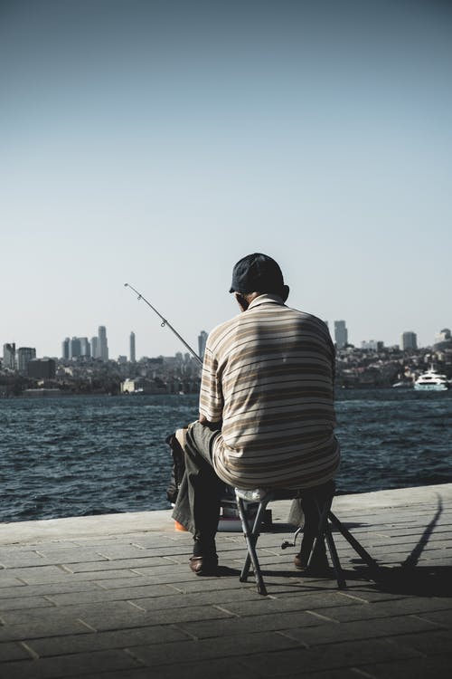 男子坐在拿着钓鱼竿 · 免费素材图片