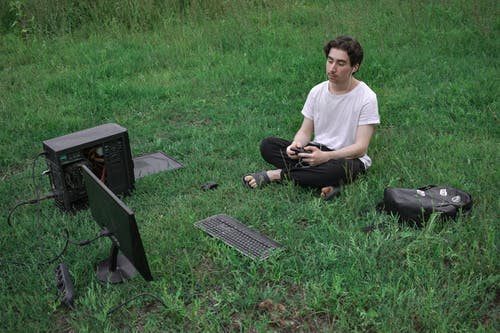 男子坐在草地上使用计算机 · 免费素材图片