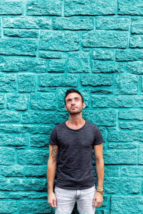 男子站在蓝绿色的混凝土墙前 · 免费素材图片