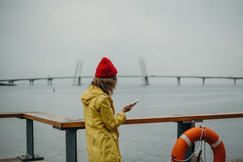 女人穿着黄色的雨衣和红色的无檐小便帽 · 免费素材图片
