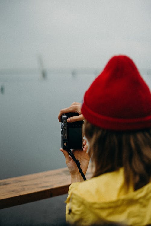 女人拿着照相机时戴着红色的针织帽 · 免费素材图片