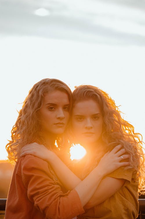 两个女人互相抱着横跨日落 · 免费素材图片