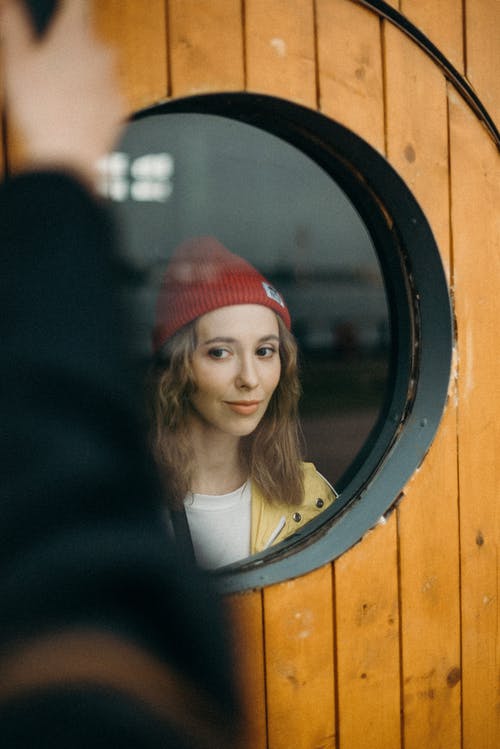 在圆形玻璃窗附近的女人的照片 · 免费素材图片