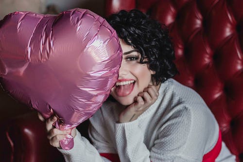 女人拿着粉红色的心形气球的照片 · 免费素材图片