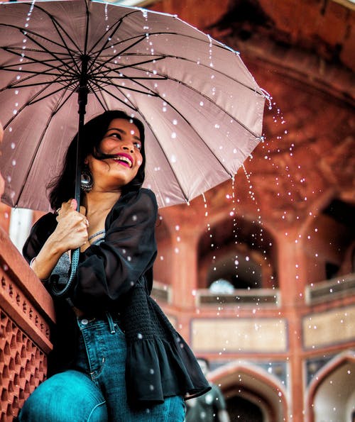 女人拿着雨伞在雨下的低角度视图 · 免费素材图片