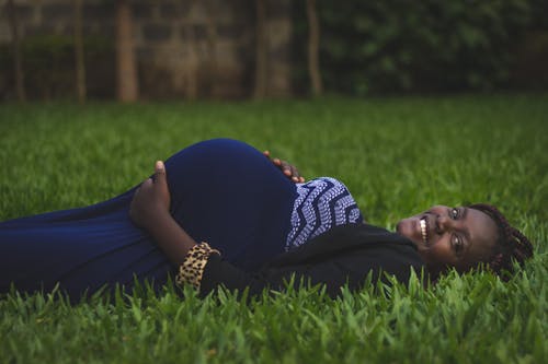 怀孕的女人躺在绿草地上 · 免费素材图片