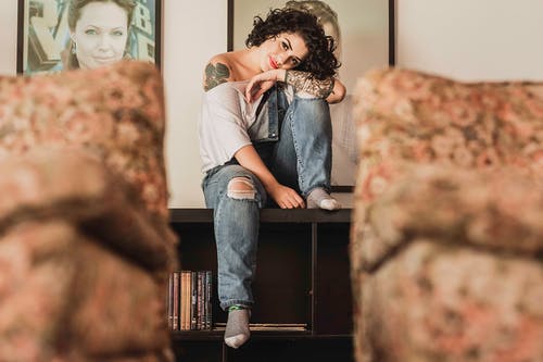 坐在书架上的女人的照片 · 免费素材图片