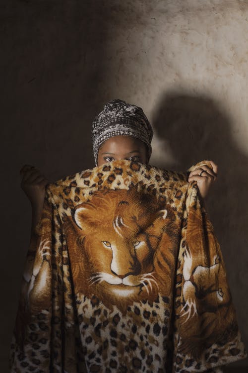 躲在毯子后面的女人的照片 · 免费素材图片