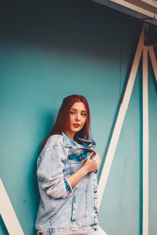 站在蓝色的墙上的女人的照片 · 免费素材图片