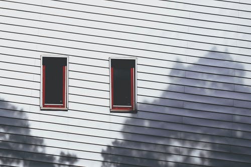 木墙上的两个窗户 · 免费素材图片