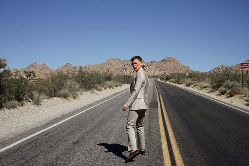 穿着灰色正式西装，在沥青路面上行走的人 · 免费素材图片