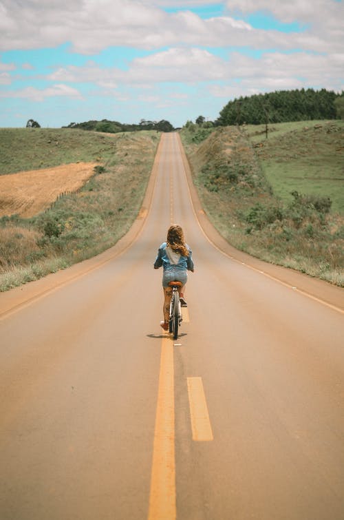 白天在路中间的女孩骑自行车 · 免费素材图片