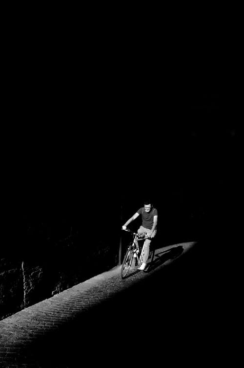 人骑自行车的灰度照片 · 免费素材图片