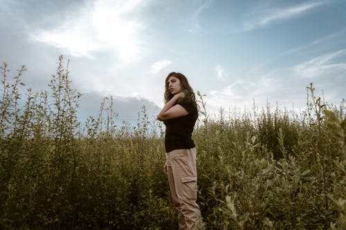 女人站在高高的草丛附近 · 免费素材图片