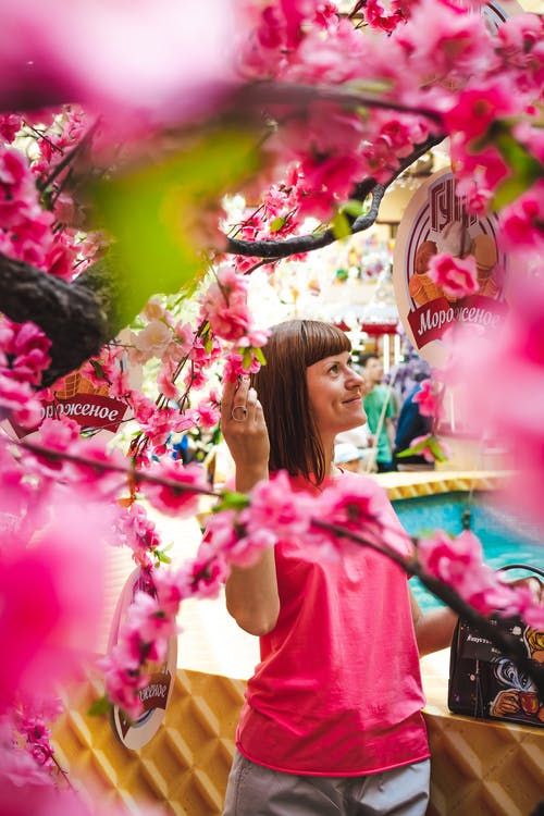 女人站在开花的树下 · 免费素材图片