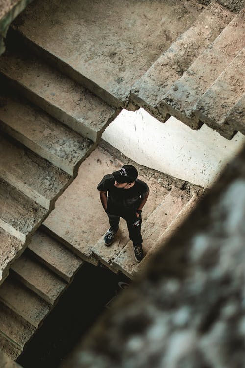 身穿黑色圆领t恤站在混凝土楼梯上的男人 · 免费素材图片