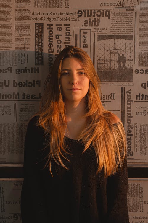 穿黑色圆领上衣的女人斜倚在墙上 · 免费素材图片