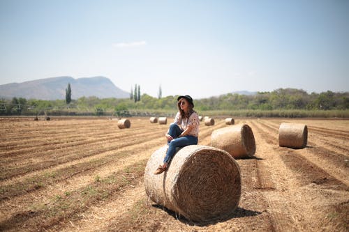 女人坐在干草捆上 · 免费素材图片