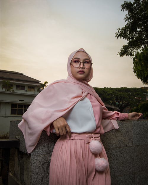 石头墙构成的粉红色盖头的穆斯林妇女的照片 · 免费素材图片
