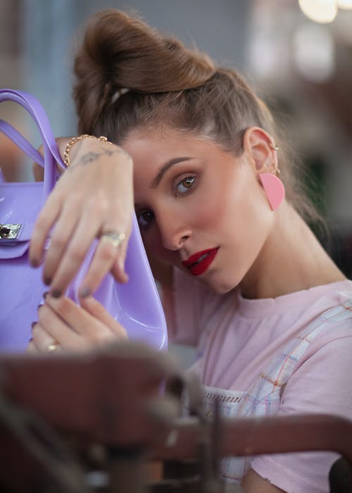 粉红色的t恤，紫色的袋子摆姿势的女人的特写照片 · 免费素材图片