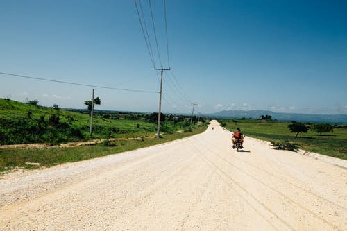 人们在道路观绿色领域骑摩托车 · 免费素材图片