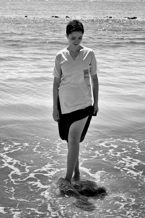 女人站在海滩上的单色照片 · 免费素材图片