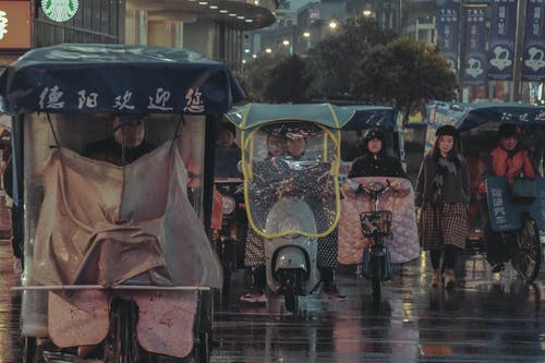 在雨中骑自行车或摩托车并行走的人 · 免费素材图片
