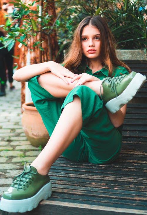 女人穿着绿色衣服，坐在木质表面上的照片 · 免费素材图片