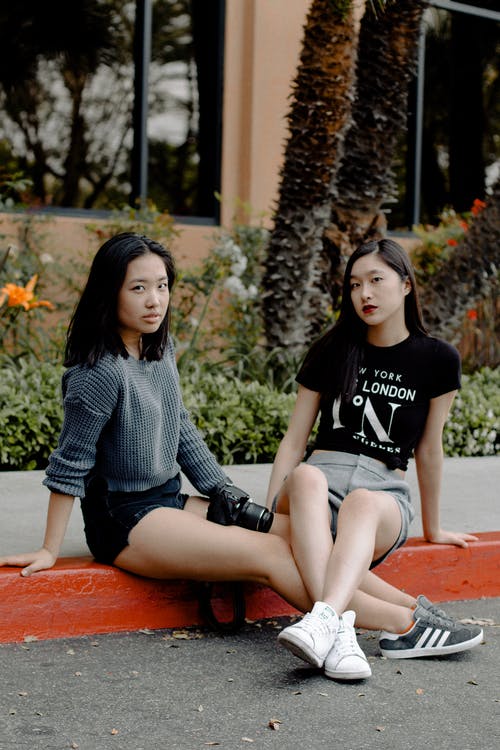 两个女人坐在路边摆姿势的照片 · 免费素材图片
