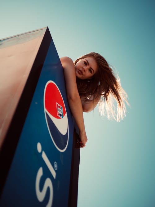 女人在百事可乐冰箱摆姿势的低角度照片 · 免费素材图片