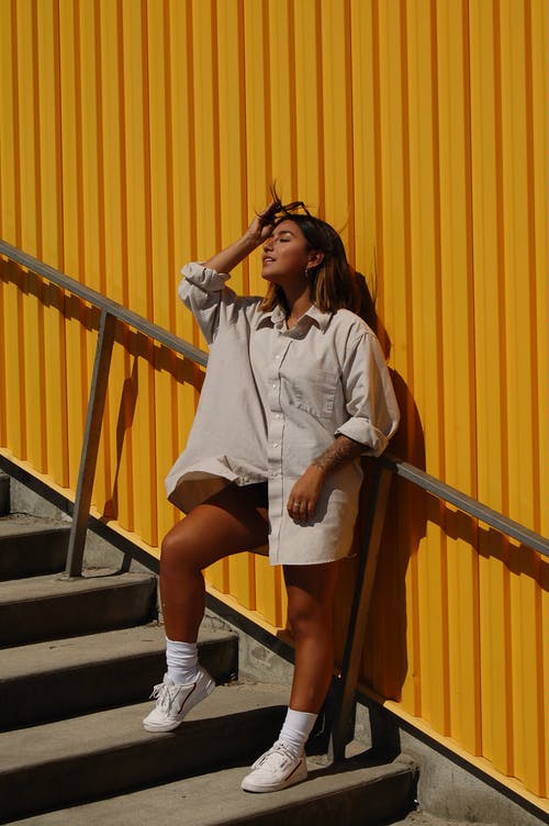 女人穿着长袖衬衫摆在楼梯上 · 免费素材图片
