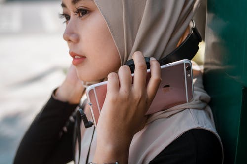 女人拿着米色头巾戴苹果我给智能手机打电话 · 免费素材图片