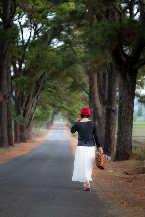 站在混凝土道路上树木中间的女人 · 免费素材图片