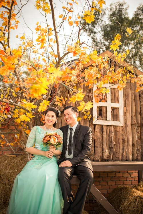 新娘和新郎坐在木椅上 · 免费素材图片