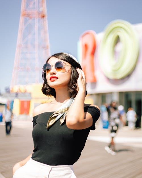 女人穿着黑色的露肩上衣和太阳镜的选择性焦点照片 · 免费素材图片