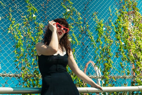 倚在钢栏杆上的黑色礼服的女人 · 免费素材图片