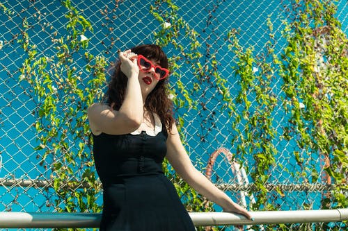 倚在钢栏杆上的黑色礼服的女人 · 免费素材图片