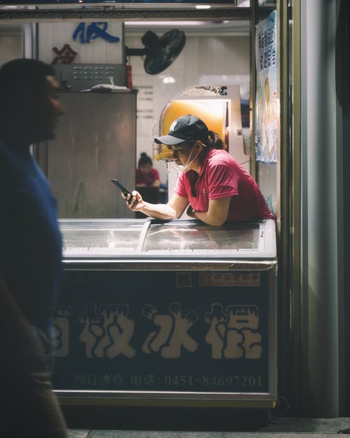 人走在街上附近倚在冰淇淋冰箱上的女人 · 免费素材图片