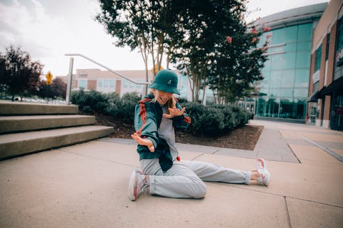 女人坐在室外附近的人行道上 · 免费素材图片