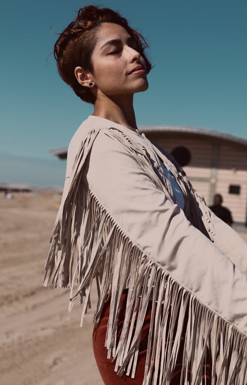 女人穿着米色长袖衬衫与条纹摆在她的眼睛的选择性焦点侧视图照片 · 免费素材图片