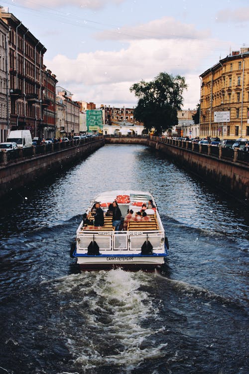 白色和蓝色的小船，在城市河上的照片 · 免费素材图片