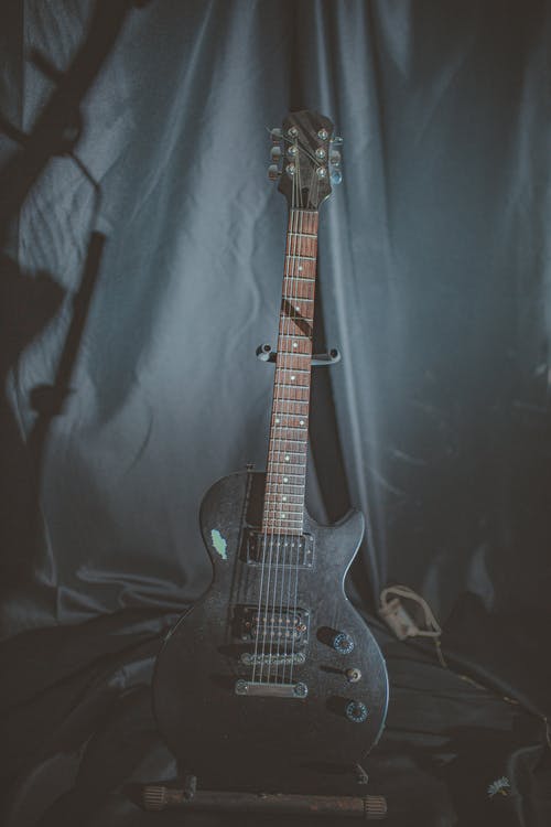 黑色电吉他在前面的黑色服装的吉他架子上 · 免费素材图片