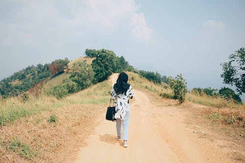 后视图照片黑盖头的女人独自走在土路上 · 免费素材图片