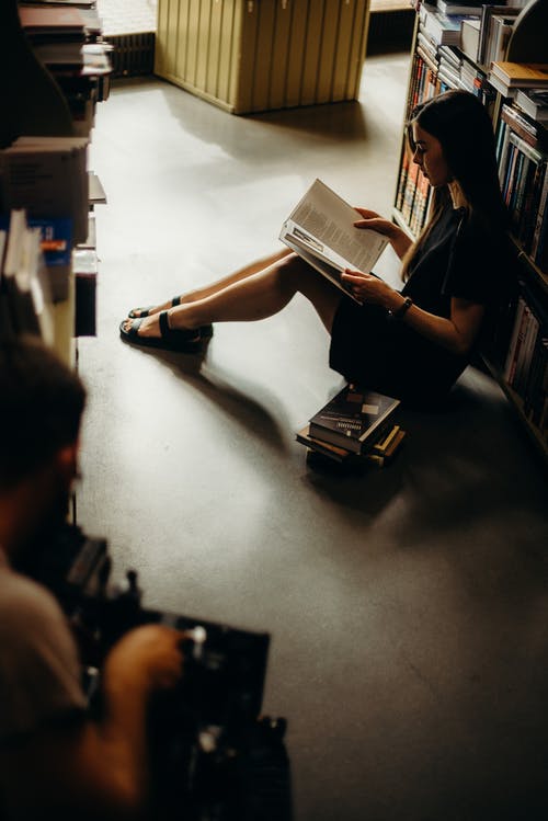 女人坐在地板上看书 · 免费素材图片