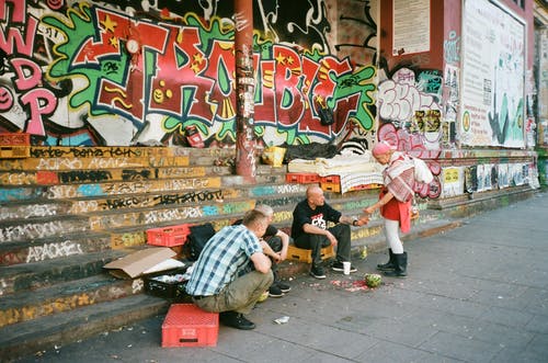 站在三个男人坐在楼梯上的男人 · 免费素材图片