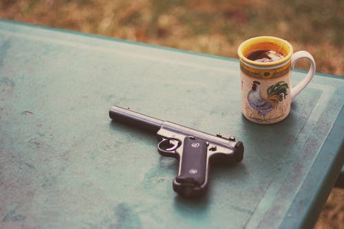 手枪在杯子附近的照片 · 免费素材图片