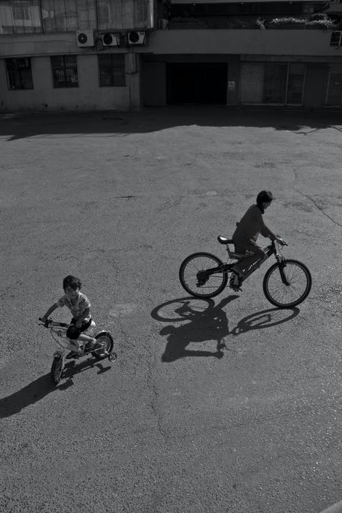 两个男孩骑自行车的灰度照片 · 免费素材图片