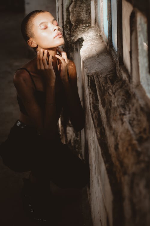 坐在墙上旁边的女人的照片 · 免费素材图片